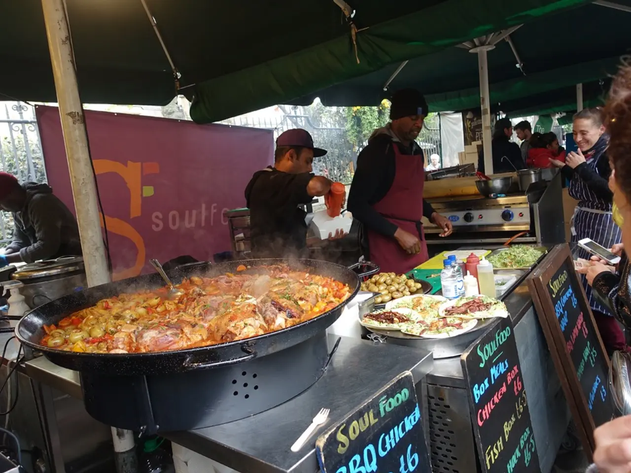 There is a food stall presenting in this picture. There are group of people standing and wearing...