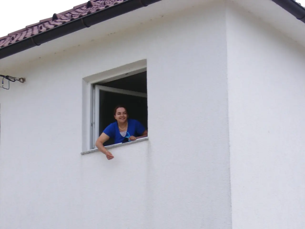 In this image I can see white colour building, windows, green colour gate and I can also see two...