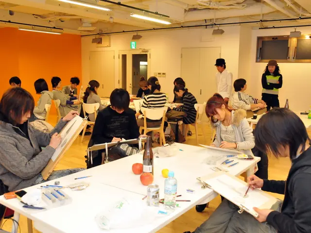 In this image there are group of persons sitting and painting at the foreground of the image there...