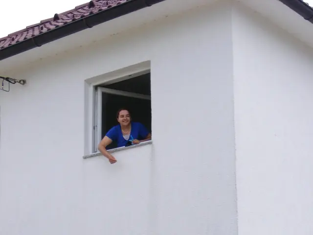 In this image I can see white colour building, windows, green colour gate and I can also see two...