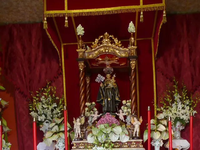 In this image there are idols on the table having flower vases and candle stands. There are candles...